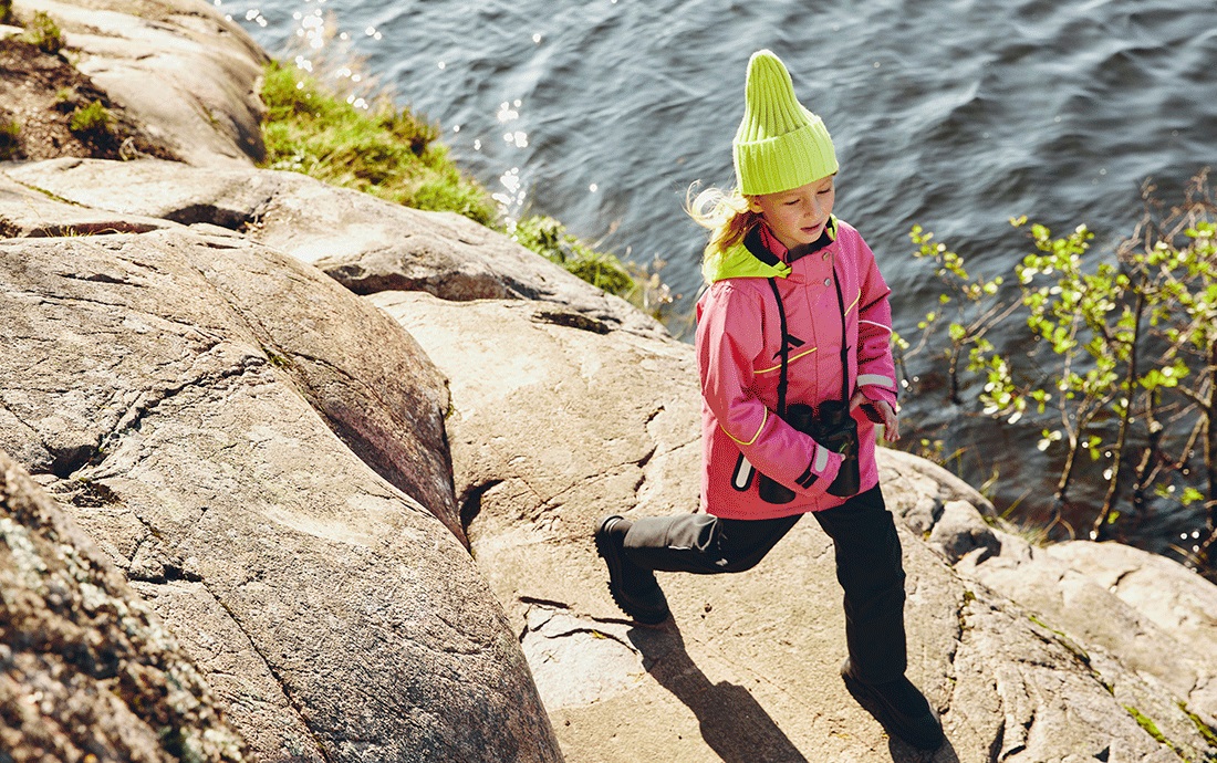 Девочка на скалах у водоёма с фотоаппаратом.