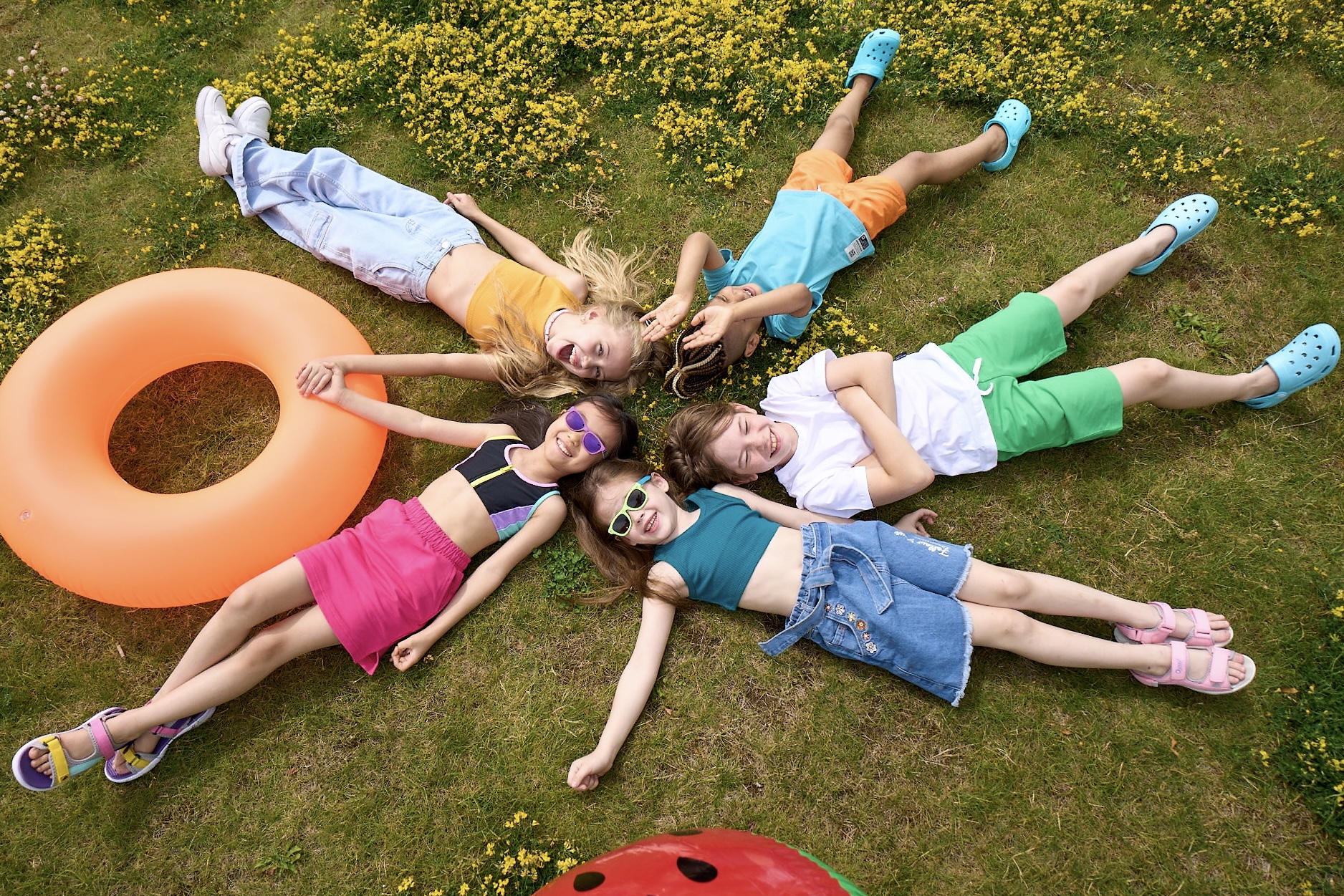 Дети в летней одежде лежат на траве.