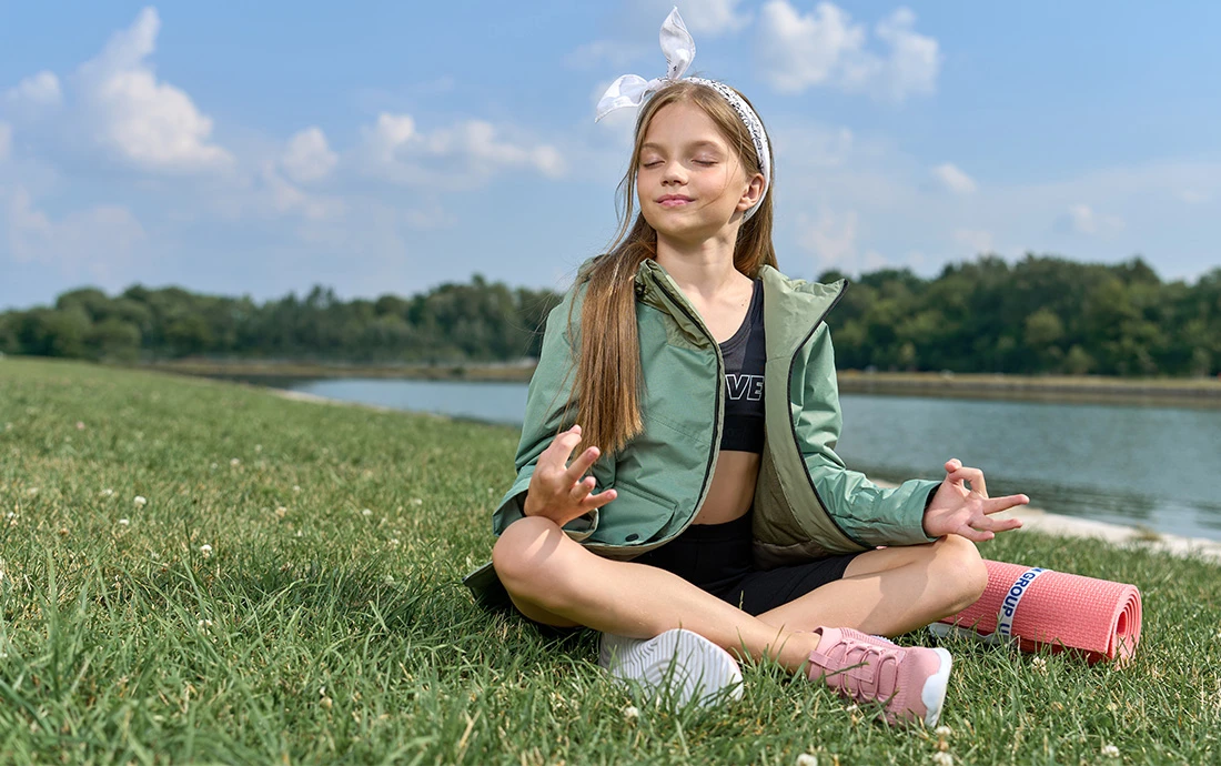 Девочка медитирующая на фоне природы.