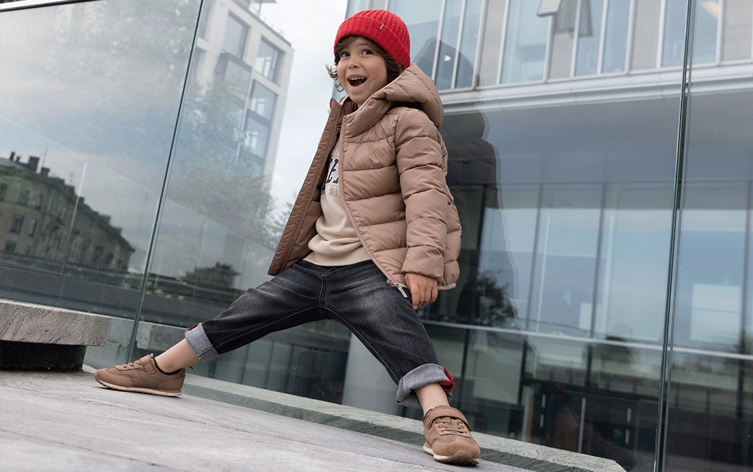 Мальчик у стены стеклянного здания.